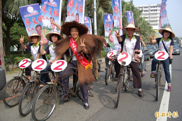 新營忠政里長的候選人廖文福穿簑衣，出動8輛骨董腳踏車掃街拜票，宣傳造勢很吸睛。（記者楊金城攝）