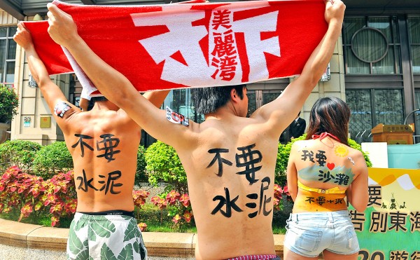 Protesters in front of the Miramar Garden Hotel in Taipei on April 17 last year hold towels bearing the slogan “Demolish the Miramar Resort,” referring to an unfinished beachfront development in Taitung County.
Photo: Chang Chia-ming, Taipei Times