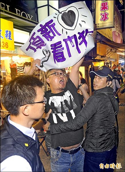 總統馬英九昨晚陪同國民黨台北市長候選人連勝文到西門商圈拜票，有民眾高舉標語嗆聲，隨即被警方架離。（記者廖振輝攝）