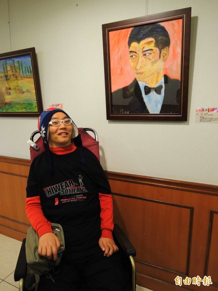 口畫家周瑞澤於高雄長庚一樓走廊展示畫作，他說，「當完成第一幅畫，感覺的是我存在，還活著」。
背景為畫作劉德華。（記者黃旭磊攝）