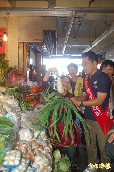 愛心菜販陳樹菊（左）送上蒜苗、菜頭給黃健庭，祝他高票連任。（記者張存薇攝）