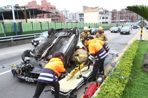 該車四輪朝天，消防員正將女駕駛拉出。（記者吳政峰攝）