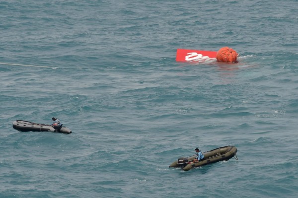 印尼海軍利用漂浮球勾住機尾，搭配海面上船隻搭載的起重機，將機尾拉出海底。（路透社）