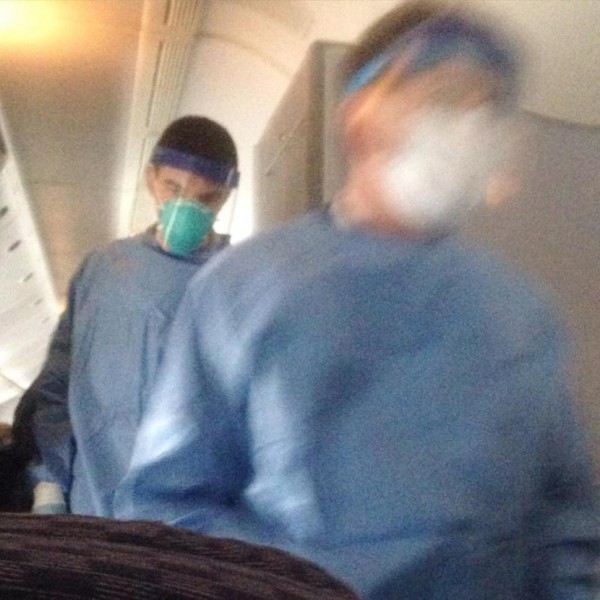 聯合航空疑似有一名女乘客感染伊波拉病毒，一名機上乘客將美國醫療人員上機將女乘客帶走的狀況拍下。（照片擷取自推特）