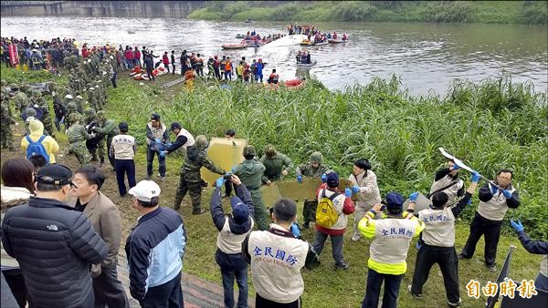 救援人員先將飛機機門及機腹內行李拿出來，以便入內救人。（記者姚岳宏攝）