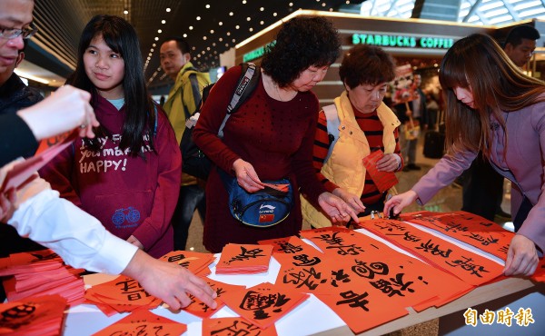 春聯成為旅客最愛帶回自己國家的紀念品，旅客正仔細挑選寫好的春聯。（記者姚介修攝）