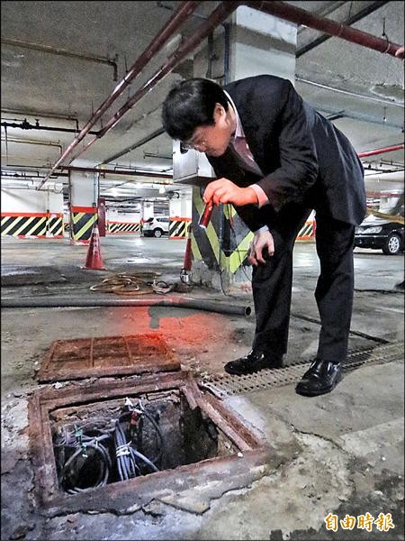 市長林右昌昨天視察東岸停車場，還請廠商將鋼板翻起，用手電筒一探究竟。（記者俞肇福攝）