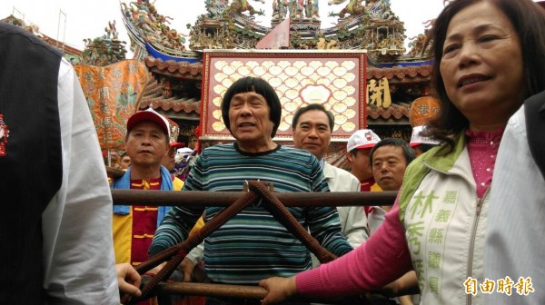 縣新港奉天宮媽祖神像經由奉天宫百年建醮志工團長的知名藝人豬哥亮（中）等人護持安奉到神轎後，浩浩蕩蕩出發。（記者謝銀仲攝）