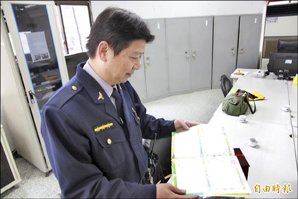 警員林振民翻閱著鍾童的聯絡簿，宛如關心兒子在校狀況的父親。（記者鄭鴻達攝）