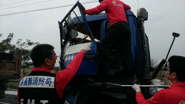 嘉義縣新港鄉連環車禍，消防人員全力搶救被卡在車體嚴重變形駕駛座內的連結車余姓司機。（記者謝銀仲翻攝）