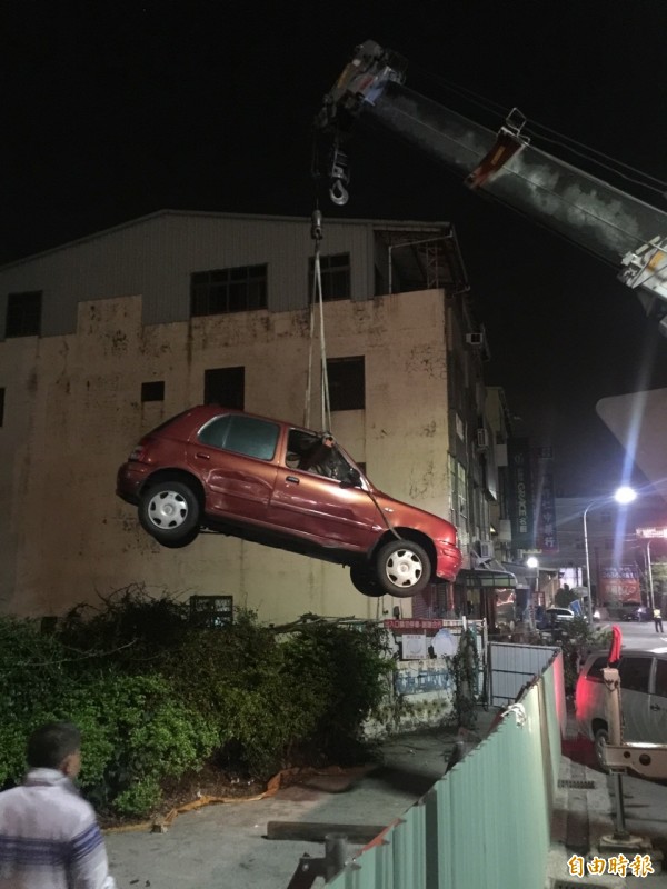 警方協助找來吊車將小客車吊出圍籬。（記者歐素美攝）