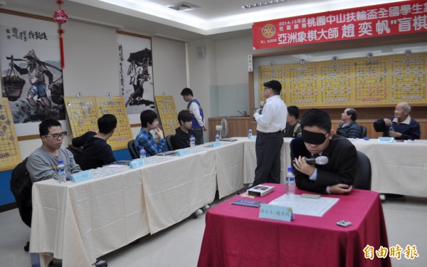 象棋國手趙奕帆（中）蒙面挑戰盲棋1對12。（記者李容萍攝）