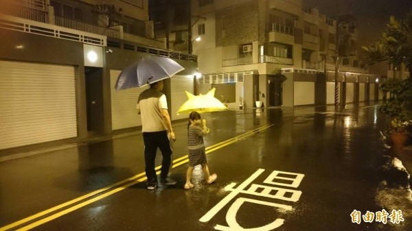 台南晚間下起雨勢，民眾難得外出撐傘。（記者林孟婷攝）