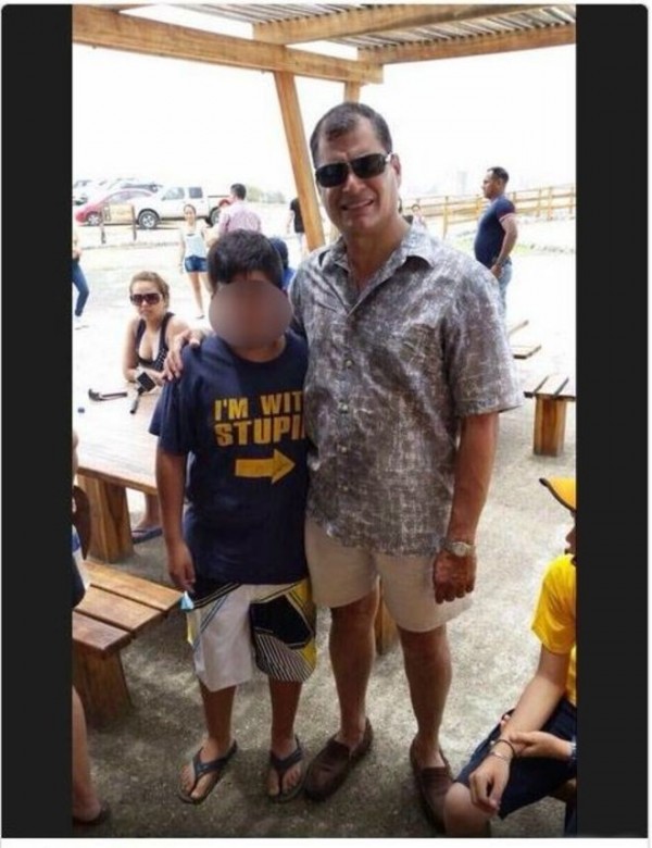 日前厄瓜多總統柯利亞和一名男童的合照在網路上瘋傳，因男童身穿「我和笨蛋一起」的T恤，而且還有一個大大箭頭「→」指著身旁的總統。（圖擷自BBC） 