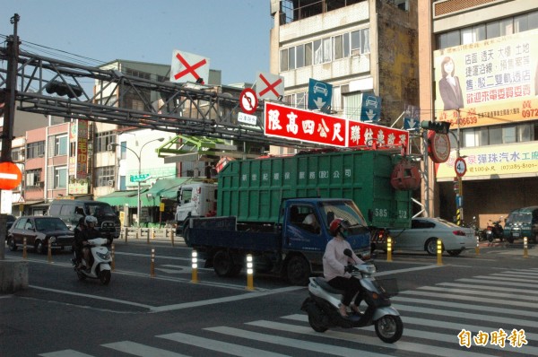 一輛大型環保車今下午4時許欲進入中華地下道時，車上附設吊桿抓斗撞擊限高架。（記者方志賢攝）