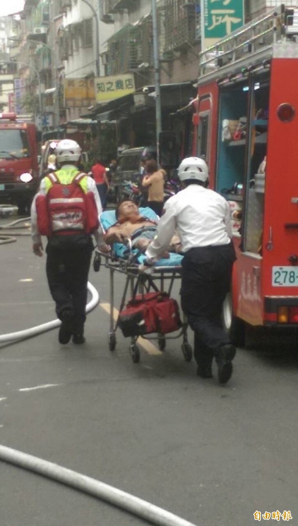 徐姓油漆工人的左手臂遭燒傷，消防人員將他送醫治療。（記者曾健銘攝）