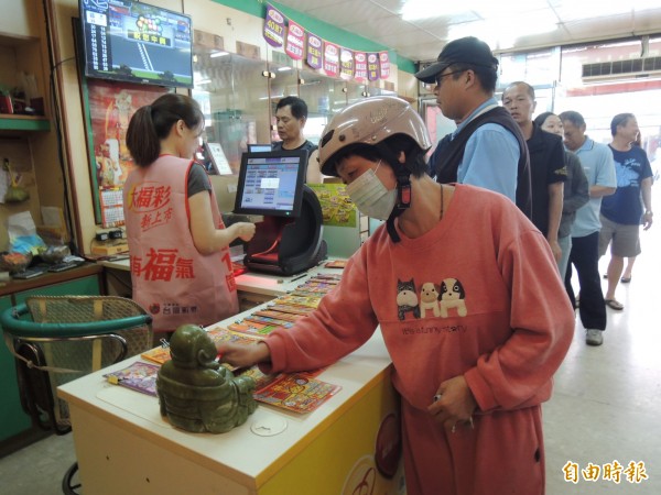 彩迷買完彩券還在財神身上擦一擦，希望鴻運降臨。（記者廖淑玲攝）