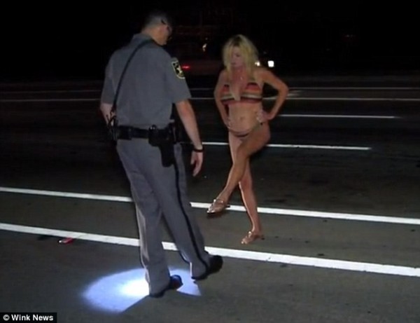 49歲的美國辣嬤載著孫子酒駕，在路邊接受警方測試單腳站立。（圖取自《每日郵報》）