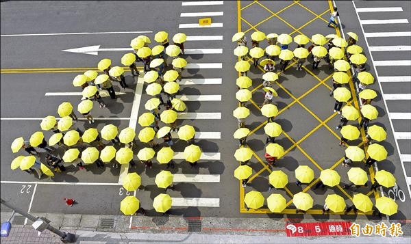 勞動節前夕，勞工團體在立院前以雨傘排出40字樣，呼籲立法院加速立法，為勞工撐起保護傘。（記者張嘉明攝）