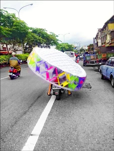 草屯街頭有位女機車騎士頭頂塑膠吹氣型的兒童泳池，緩緩前進，讓民眾大呼「大嬸好強！」（翻攝自臉書）