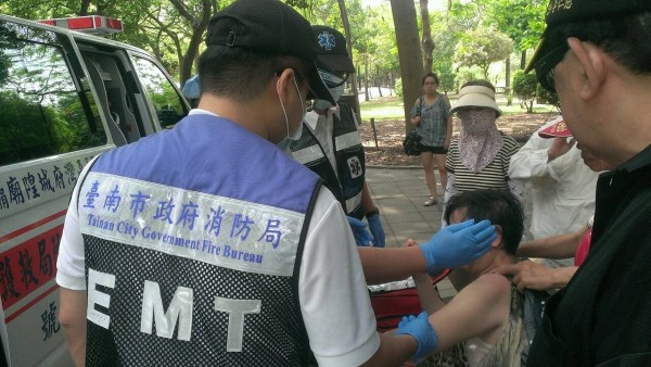 南市東區巴克禮公園內小葉欖仁樹的一根粗樹枝斷裂砸傷一婦人，消防局救護員到場處理傷勢。（記者王俊忠翻攝）