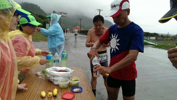 途經補給站，參賽選手拿出自備環保杯填裝礦泉水。（記者陳賢義翻攝）