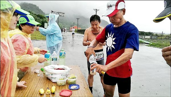 響應綠色公益，途經補給站，蘭嶼路跑參賽選手拿出自備環保杯填裝礦泉水。（記者陳賢義翻攝）