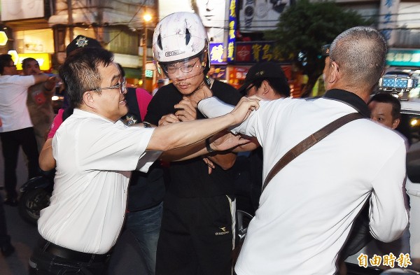 台北市北投區文化國小29日發生1名8歲女學童遭割喉案，送醫急救。警方迅速逮捕龔姓男嫌犯（中）帶回偵訊，不滿龔嫌的民眾上前追打，被警方架開。（記者廖振輝攝）