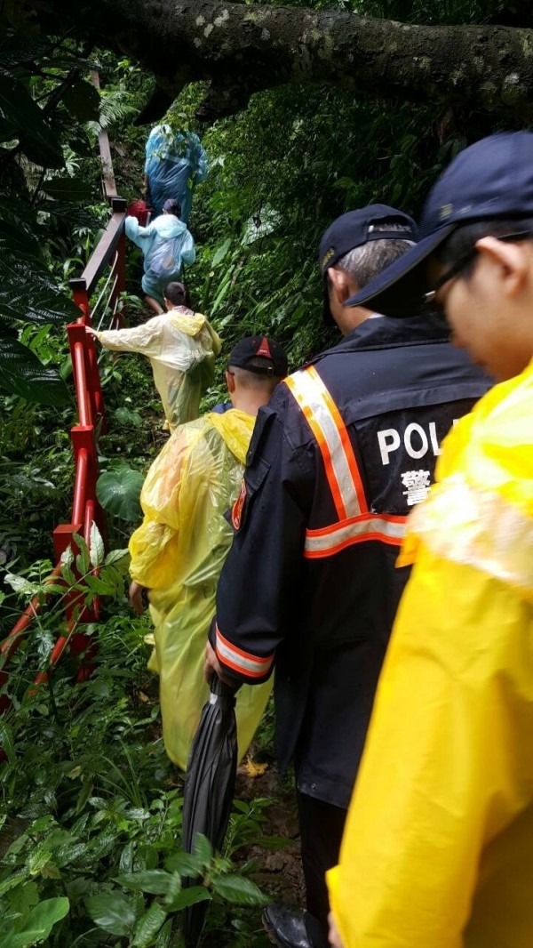 消防與警方人員送來雨衣並護送黃姓父親與三名子女安全走出山羊古道。（記者余雪蘭翻攝）