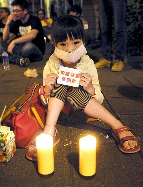 兒童權益促進協會昨晚在立法院外，發起「為台灣兒童安全與權益點一盞希望燭光」活動。一名來自彰化的女童由媽媽陪同，在現場點起蠟燭靜坐。（中央社）