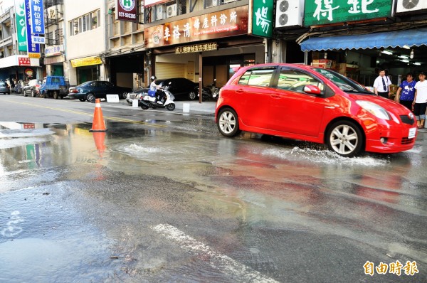 頭份鎮和平路自來水管線爆裂，過往車輛放慢通行。（記者彭健禮攝）