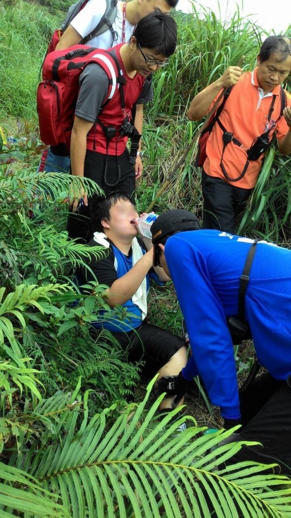 徐姓男子（坐在地上喝水者）腳抽筋受困山區，新北市瑞芳警消急救援，將他救下山。（記者林嘉東翻攝）