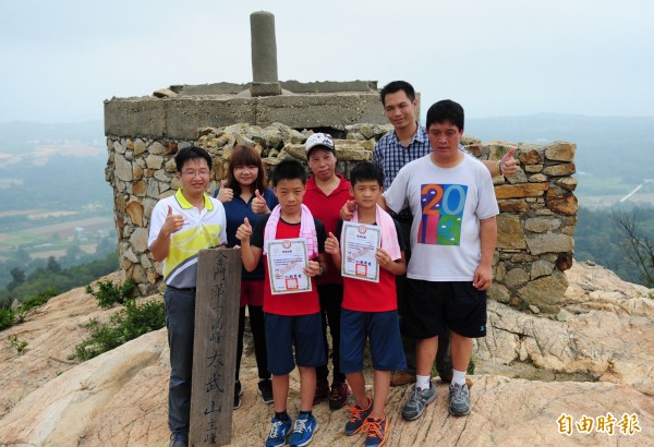 金門述美國小校長劉界宏（前左一）在太武山頂，把畢業證書頒給楊昊龍（前左二）、張煒世（前右二）。（記者吳正庭攝）