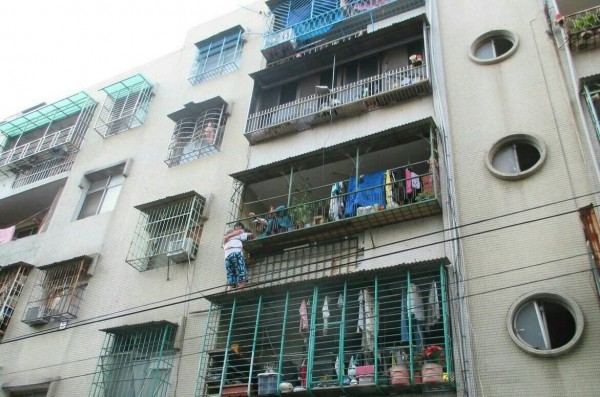 89歲老翁站遮陽板要跳樓，家屬、警方隔鐵欄抱住他。（記者鄭淑婷翻攝）