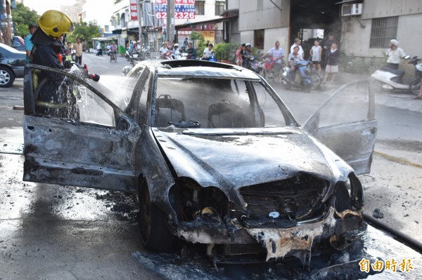 林姓女子駕駛的賓士轎車，突然冒煙並起火燃燒，消防人員以強力水柱灌救。（記者蘇福男攝）