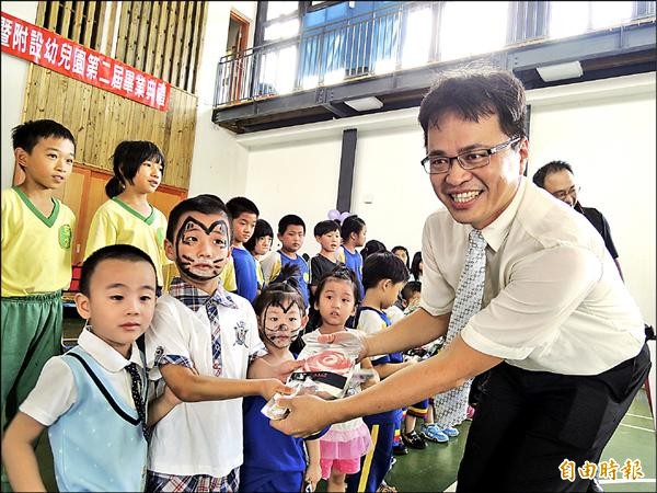 草嶺國小校長曾智豐（右）比學童更早畢業，昨贈送每位學童一枝超大棒棒糖，獎勵孩子優秀的表現。（記者黃淑莉攝）