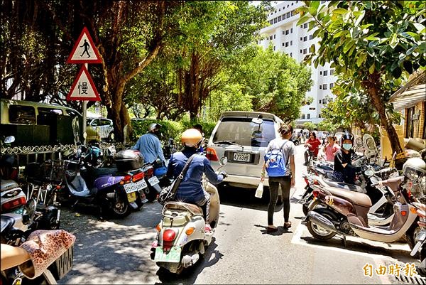 公所設置的機車格和違停的機車，導致道路縮減，人車爭道。（記者朱則瑋攝）