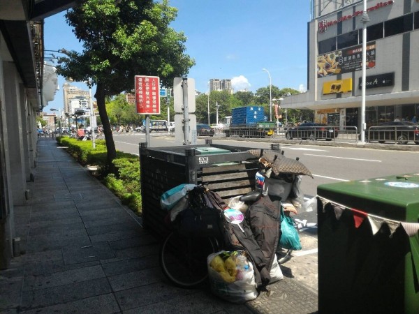 黃姓遊民蜷縮在距離警所不到百公久的路旁睡覺。（記者黃佳琳翻攝）