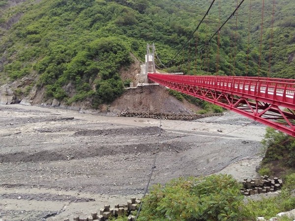 吊橋距離河床大約還有20公尺高，目前鄉公所在橋墩下先放消波塊緊急維護。（郭東雄提供）