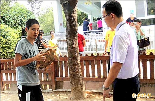 德安啟智教養院院生劉走宜（左）抱著被截肢的烏龜，向高鐵台中站站長文青雲（右）等人說明照顧烏龜的心得。（記者謝介裕攝）