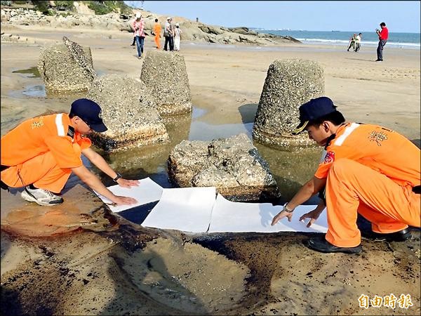 岸巡人員使用吸油棉應變。（記者吳正庭攝）