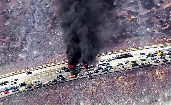 加州十五號州際公路卡洪隘口處的車輛遭野火波及燃燒，濃煙竄升天際，民眾被迫棄車逃命。（路透）