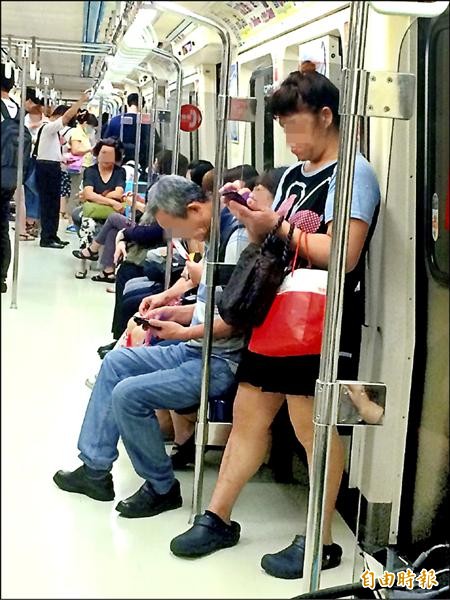 許多民眾搭乘捷運時習慣低頭使用手機，不僅影響上下車的動線，還可能罹患肩頸疾病。（記者郭逸攝）