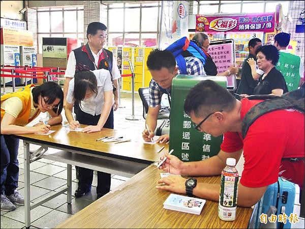 台東郵局在台東火車站大廳設置臨時郵局，讓民眾免費書寫、寄交父親節明信片，吸引許多遊客寫下對父親的感謝話語。（記者王秀亭攝）