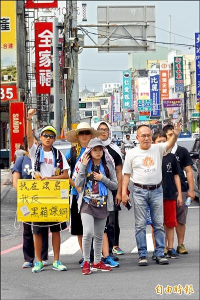 高中生許冠澤和周子翔徒步環島反黑箱課綱，昨走到屏東潮州，近10名民眾一路往南陪走，宣揚理念。（記者邱芷柔攝）