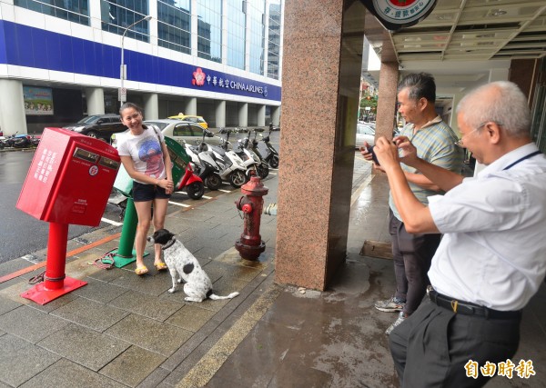 颱風蘇迪勒襲台，台北市龍江路郵筒遭掉下的招牌擊中變形，有民眾特替前來跟郵筒拍照。（記者王藝菘攝）