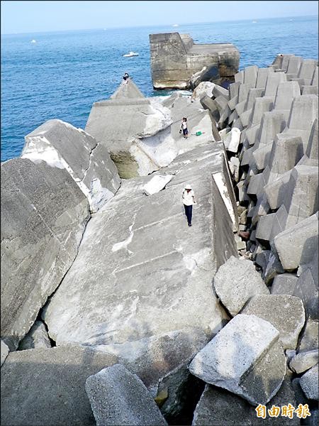 釣客在斷裂傾斜的海堤上趴趴走垂釣，令人悚目驚心。（記者盧賢秀攝）