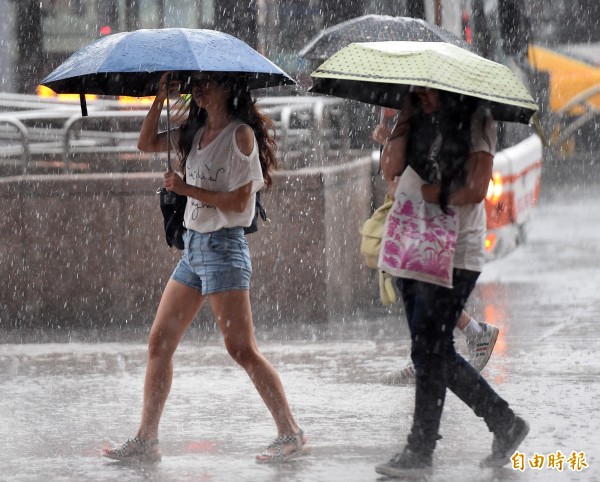 台北市昨天午後烏雲密布下起雷陣雨，驟雨讓街頭行人紛紛撐傘避雨。（資料照，記者廖振輝攝）