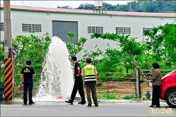 周姓婦人開車撞斷消防栓，水如噴泉湧出，她呆站在消防車旁不知所措，警消到場戒備，等候自來水公司人員協助關閉水源。（記者李忠憲攝）