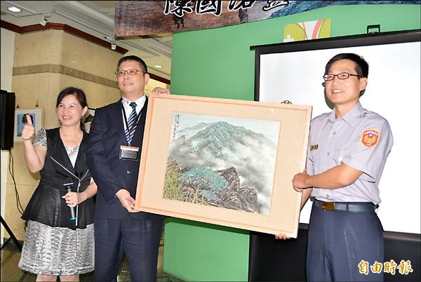 南投縣警局保防室調查員陳國洛（右）心愛的畫作「夏雲歸山」賣出8萬元，他全數捐出做公益。（記者湯世名攝）